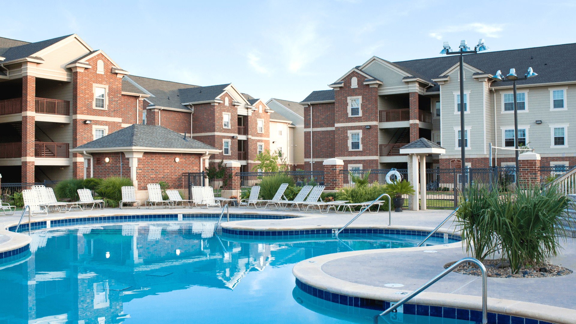 A pool with chairs and a building in the background.