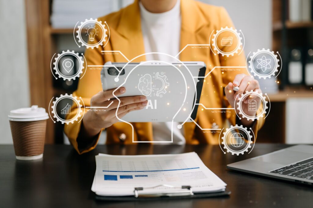 A person seated at a desk using a tablet with a graphic overlay of icons representing AI capabilities.