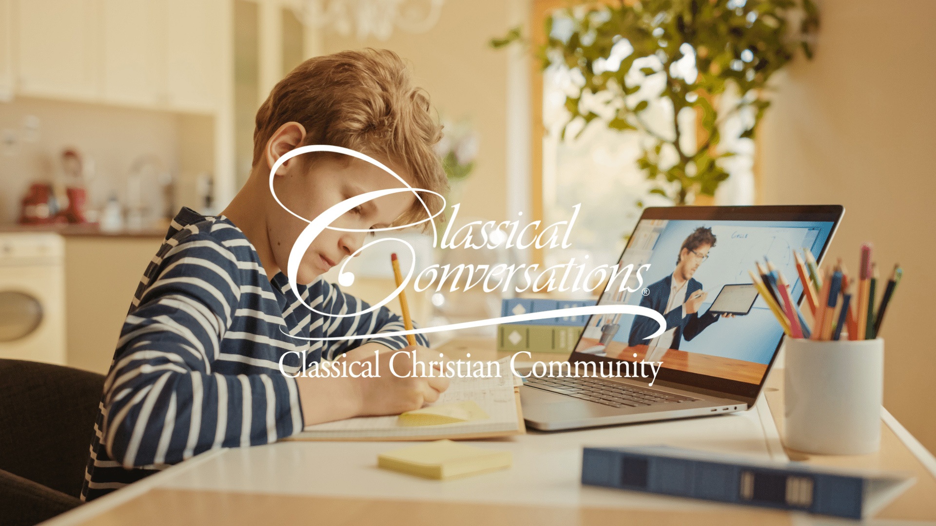 Boy writing at a desk while watching an online lesson on a laptop; Classical Conversations logo overlaid.